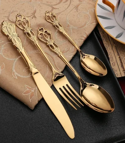 Gold flatware set with spoon, fork, and steak knife on a white tablecloth