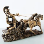 Golden Roman chariot sculpture with warrior and two horses, front view on white background.