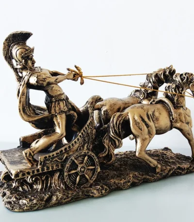 Golden Roman chariot sculpture with warrior and two horses, front view on white background.