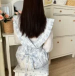 Woman wearing a cotton apron for baking with fresh plaid pattern and ruffled edges in a rustic kitchen