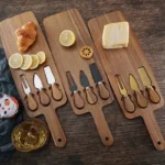 Acacia cheese board set with cheese knives and wooden cutting board on a table
