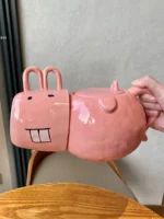 Funny pig teapot pouring tea from its snout on a kitchen counter