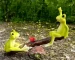 Fairy garden frog couple on a wooden seesaw in a miniature garden setting