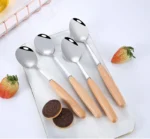 Stainless steel flatware set with wooden handles displayed on a table