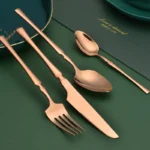 Goldoma 16-piece stainless steel silverware set with forks, knives, and spoons on a wooden table