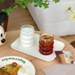 Set of glass cups with straws on a wooden table, filled with iced tea and lemon