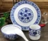 Blue white dinnerware set with bone china plate, bowl, tea cup, and spoon on a wooden table