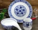Blue white dinnerware set with bone china plate, bowl, tea cup, and spoon on a wooden table
