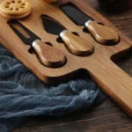 Acacia cheese board set with cheese knives and wooden cutting board on a table