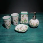 Floral lotion bottle in ceramic, placed beside toothbrush holder, on wooden bathroom shelf.