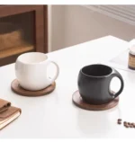 Elegant ceramic coffee mug set with saucer on wooden table, featuring oat-colored cups
