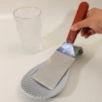 Silicone spoon rest holding a wooden spoon on a kitchen counter