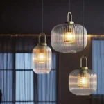 Japanese style glass pendant light with clear glass shade and black cord, hanging over a wooden dining table.