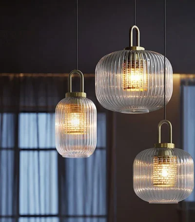 Japanese style glass pendant light with clear glass shade and black cord, hanging over a wooden dining table.