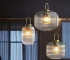 Japanese style glass pendant light with clear glass shade and black cord, hanging over a wooden dining table.