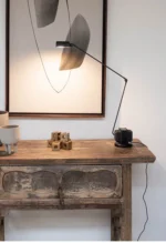 Black floor lamp with a round base, placed on a rug in a contemporary living space.