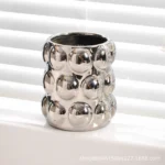 Two electroplated ceramic mugs placed symmetrically on a bathroom counter, reflecting light.