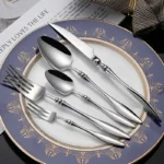 Elegant French stainless steel cutlery set with pointed tail handles on a wooden table
