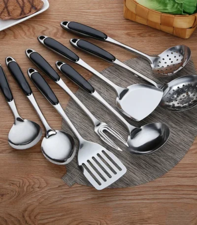 Stainless steel cooking utensils set with spatula, soup spoon, and shovel on a kitchen counter