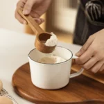 Enamel baking measuring cup with dual scale markings on a kitchen counter