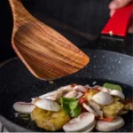 Wooden cooking utensils set with spatula, soup ladle, and rice scoop on a kitchen counter