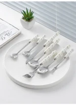 Stainless steel flatware set with ceramic pearl handles on wooden table