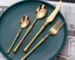 Matte gold flatware set with antique finish arranged on a wooden table