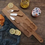 Acacia cheese board set with cheese knives and wooden cutting board on a table
