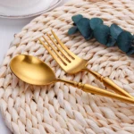 Matte gold flatware set with antique finish arranged on a wooden table