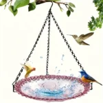Garden decoration: hanging bird bath with a blue ceramic bowl and metal chain against a brick wall.