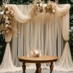 Sheer white wedding arch draping fabric elegantly draped over a wooden arch at an outdoor ceremony