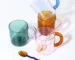 Borosilicate glass mug with coffee and glass spoon on a wooden table