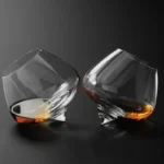 Rotating whiskey glass on a wooden table with amber liquid swirling inside