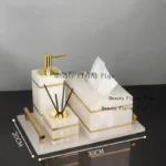 Set of marble bathroom accessories arranged on white surface.