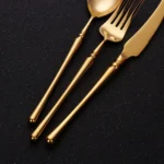 Matte gold flatware set with antique finish arranged on a wooden table