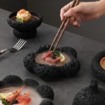 Volcanic stone sushi plate with fresh sushi rolls and wasabi on a dark textured surface