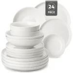 Elegant ceramic plates set with dinner plates, dessert plates, cereal bowls, and soup bowls arranged on a wooden table