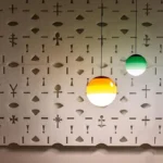 Gray glass ball pendant lamp with a metallic ceiling plate, shown against a white wall.