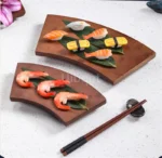 Bamboo sushi serving tray with assorted sushi rolls and sashimi on a wooden table