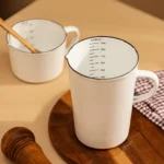 Enamel baking measuring cup with dual scale markings on a kitchen counter