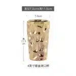 Goldoma ceramic soap dispenser with golden accents, front view on white marble.