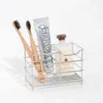 Creative stainless steel toothbrush holder in black, wall-mounted, holding two toothbrushes and a toothpaste tube.