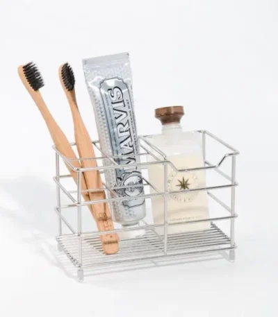 Creative stainless steel toothbrush holder in black, wall-mounted, holding two toothbrushes and a toothpaste tube.