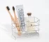 Creative stainless steel toothbrush holder in black, wall-mounted, holding two toothbrushes and a toothpaste tube.