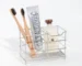 Creative stainless steel toothbrush holder in black, wall-mounted, holding two toothbrushes and a toothpaste tube.
