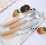 Stainless steel flatware set with wooden handles displayed on a table