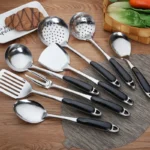 Stainless steel cooking utensils set with spatula, soup spoon, and shovel on a kitchen counter