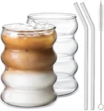 Set of glass cups with straws on a wooden table, filled with iced tea and lemon