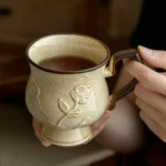 Medieval ceramic mug with hibiscus relief design on a wooden table