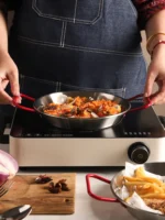 Stainless steel paella pan with double ears on a stove